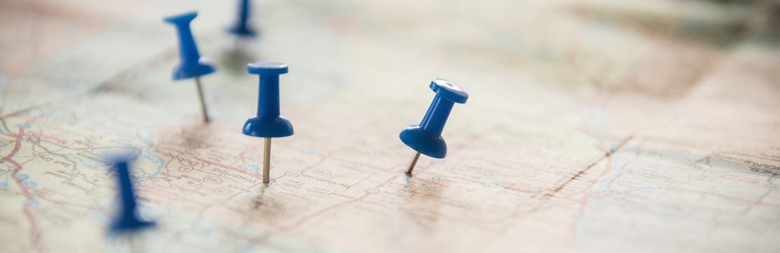 A close-up shot of blue thumbtacks pushed into a map.